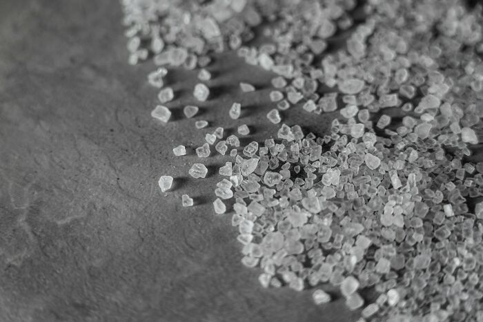 Coarse salt crystals scattered on dark stone background