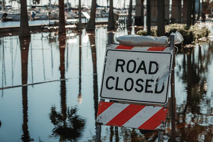 Road closed sign in flooded area with reflections of trees in water