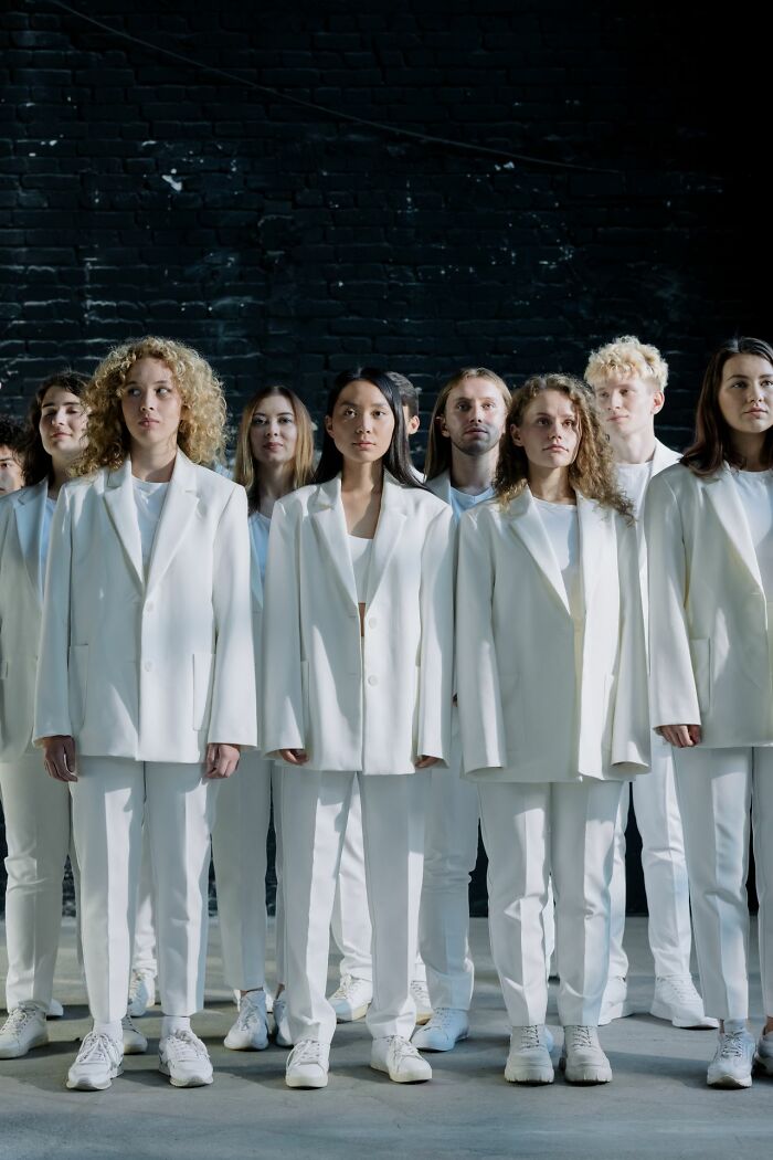 A diverse group of people in white suits, standing together, hinting at who is secretly very smart.