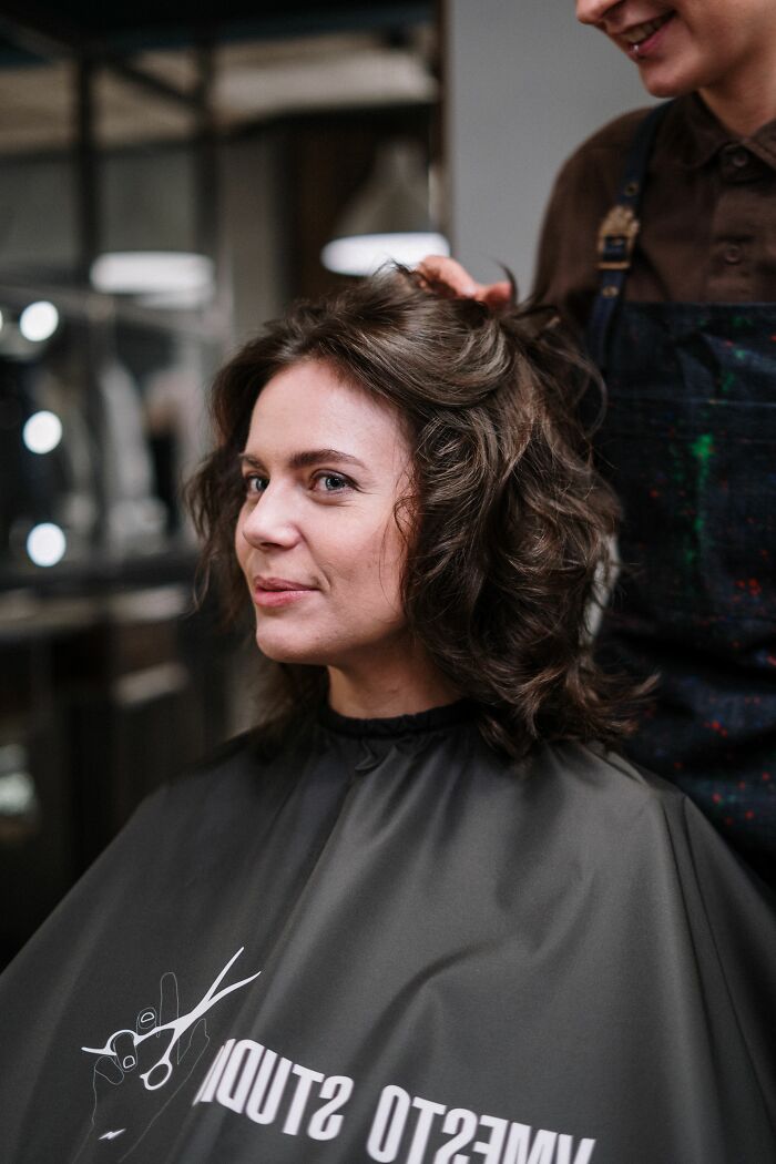 Woman in a salon chair, her hair being styled; a moment where someone might misread social cues.
