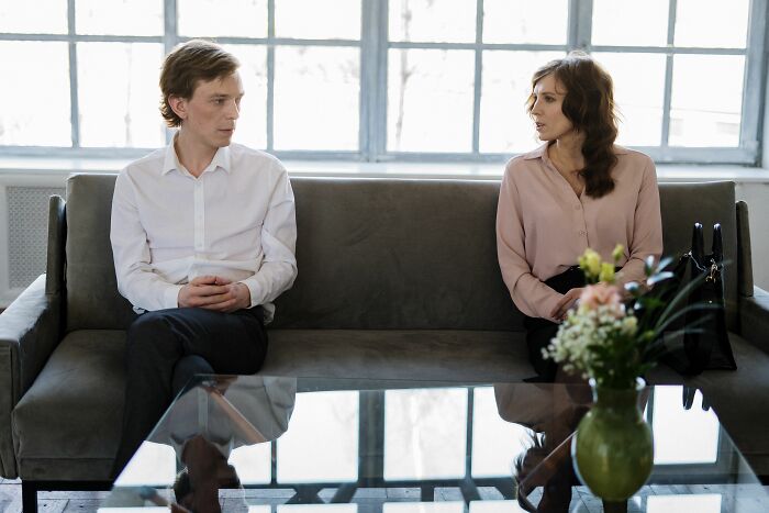 Couple sitting on couch having serious conversation indoors