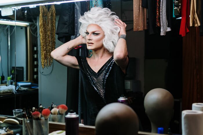 Person with white wig and makeup in dressing room preparing for performance