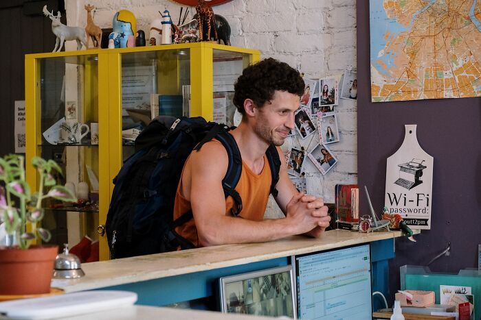 A man with a backpack smiling at a counter, suggesting an interesting coincidence during his travels.