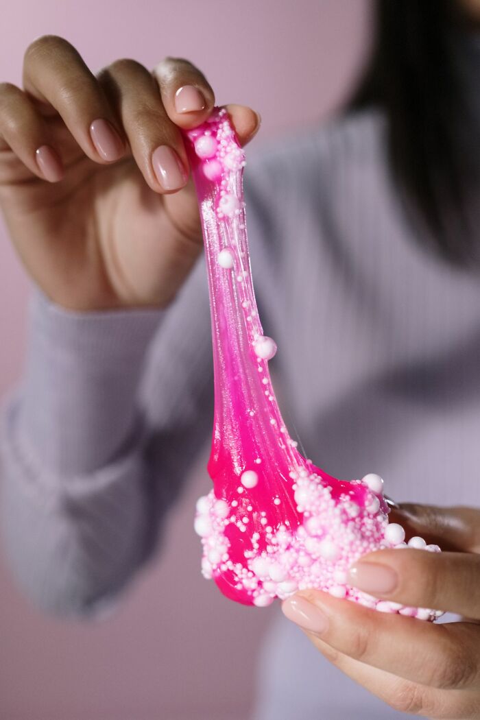 Hands stretch pink slime with white foam beads, a playful item that might relate to an unserious ER visit.