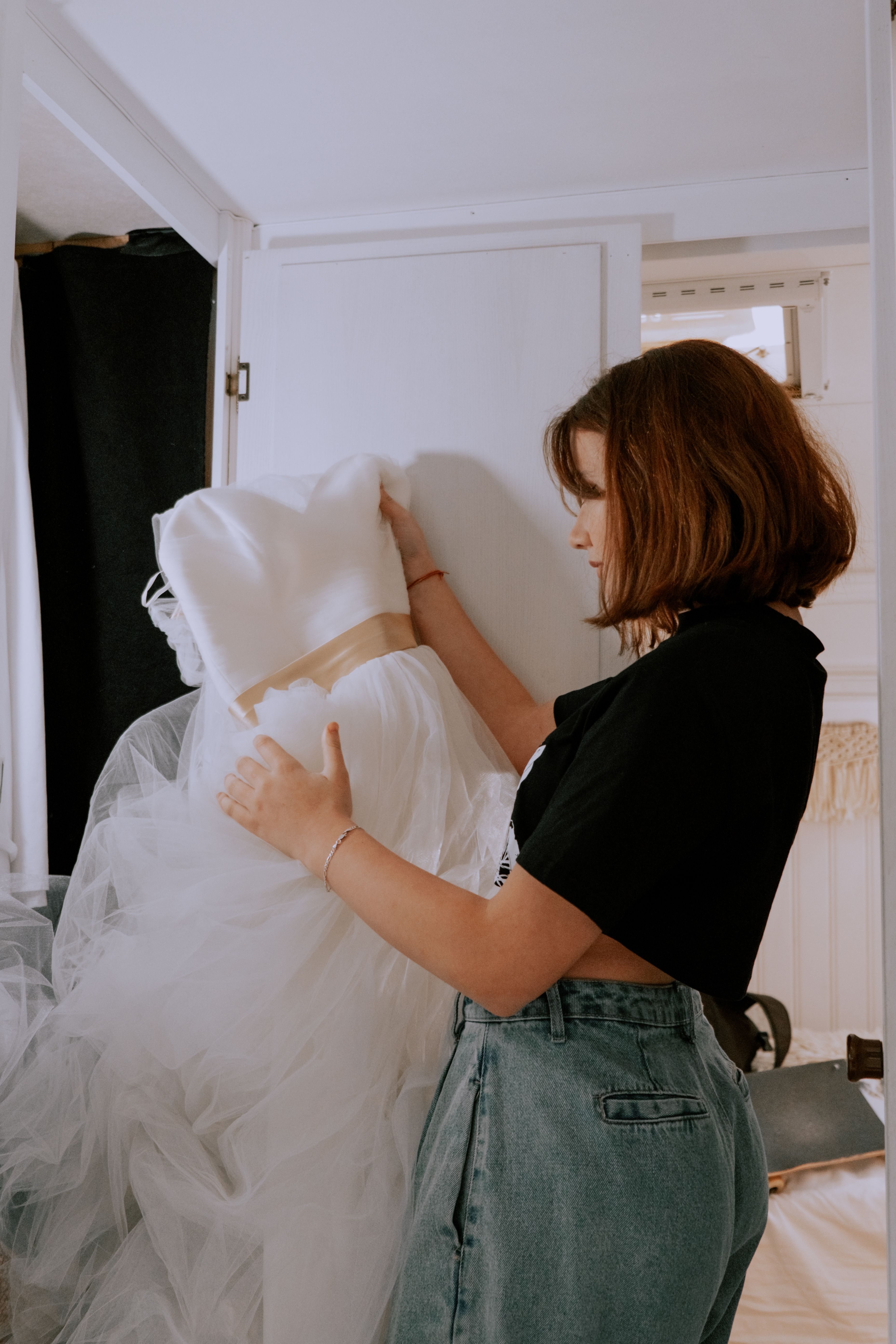 Daughter holding a wedding dress, contemplating her wedding plans amidst mom's birthday demands. Daughter holding a wedding dress, contemplating her wedding plans amidst mom's birthday demands.