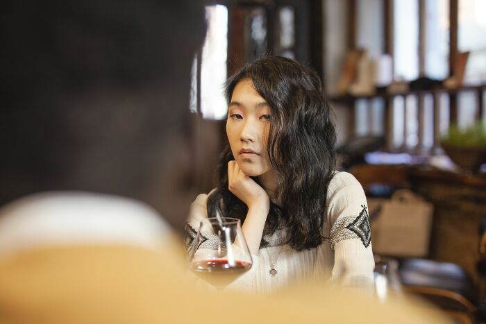 A woman looking bored with a glass of red wine, expressing turn offs during a conversation.