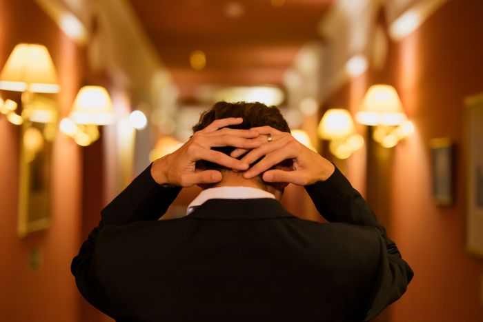 Man in suit holding head in hallway illustrating panic attack at wedding Man in suit holding head in hallway illustrating panic attack at wedding
