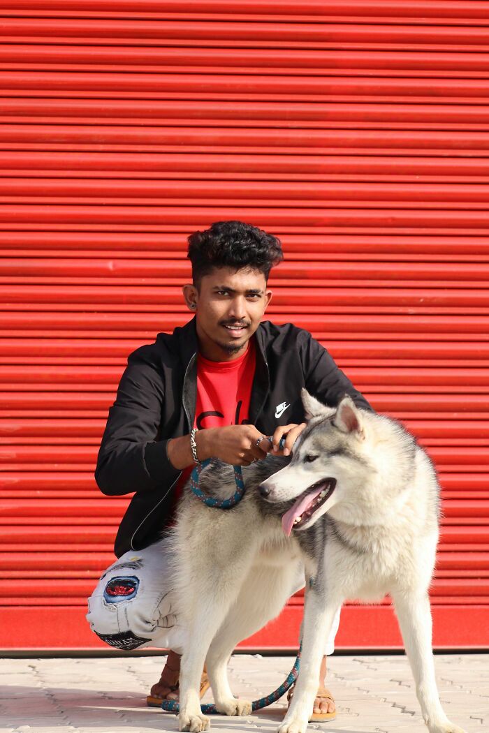 A man with a dog, posing in front of a red shutter. Exploring NSFW facts about human bodies.