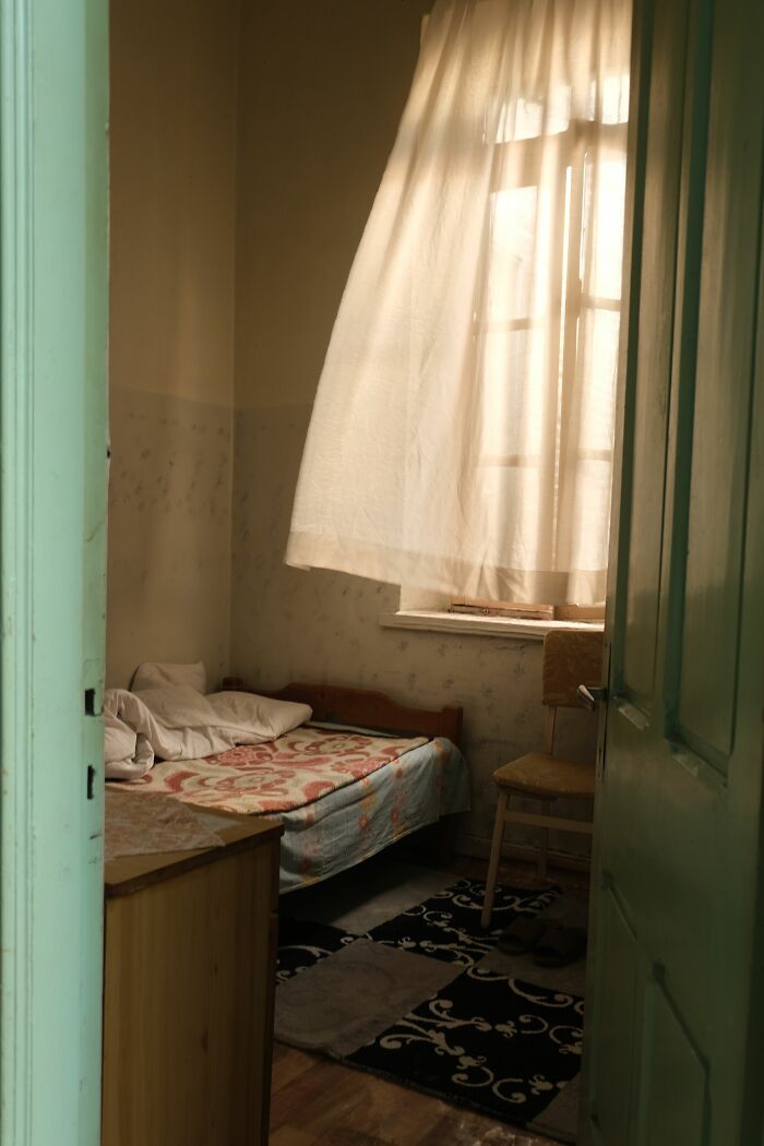 A small, humble bedroom with a bed, chair, and sunlight through a window, symbolizing people who hid their true selves.