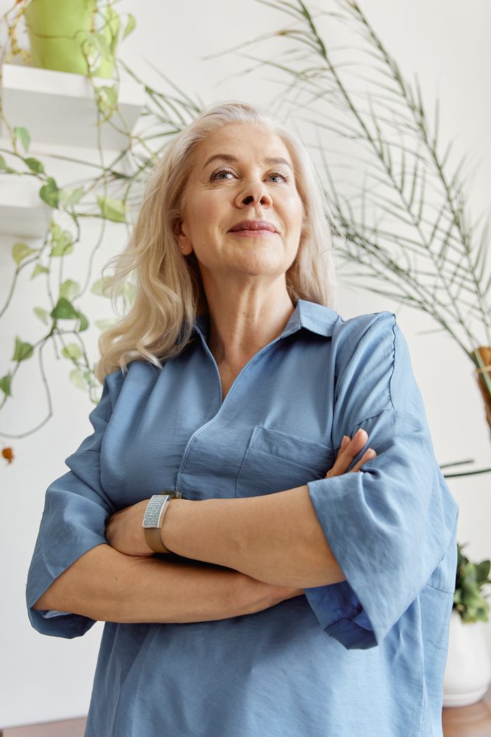 Confident middle aged woman with arms crossed indoors