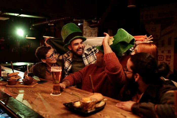 Group of friends enjoying drinks and food at a pub during a general knowledge quiz night