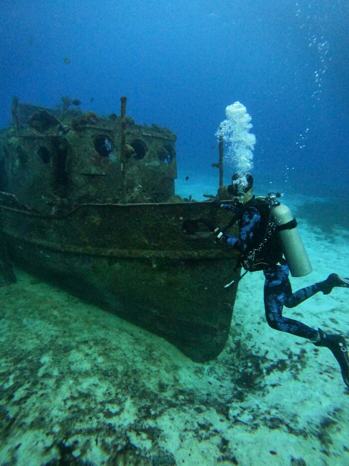 Diver exploring sunken shipwreck underwater