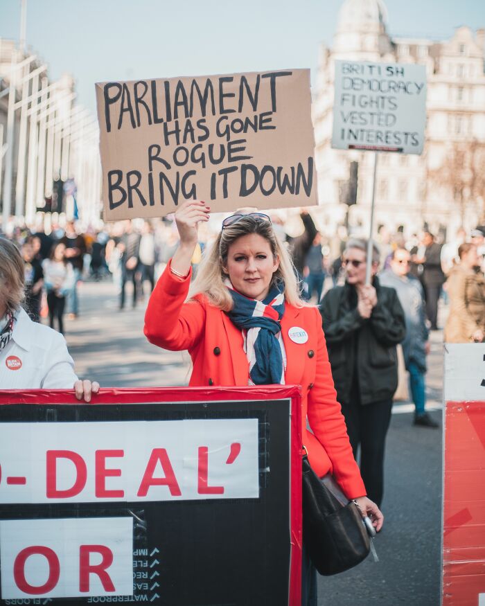 A woman holding a sign in a crowd, rolling her eyes at mens turn-offs.