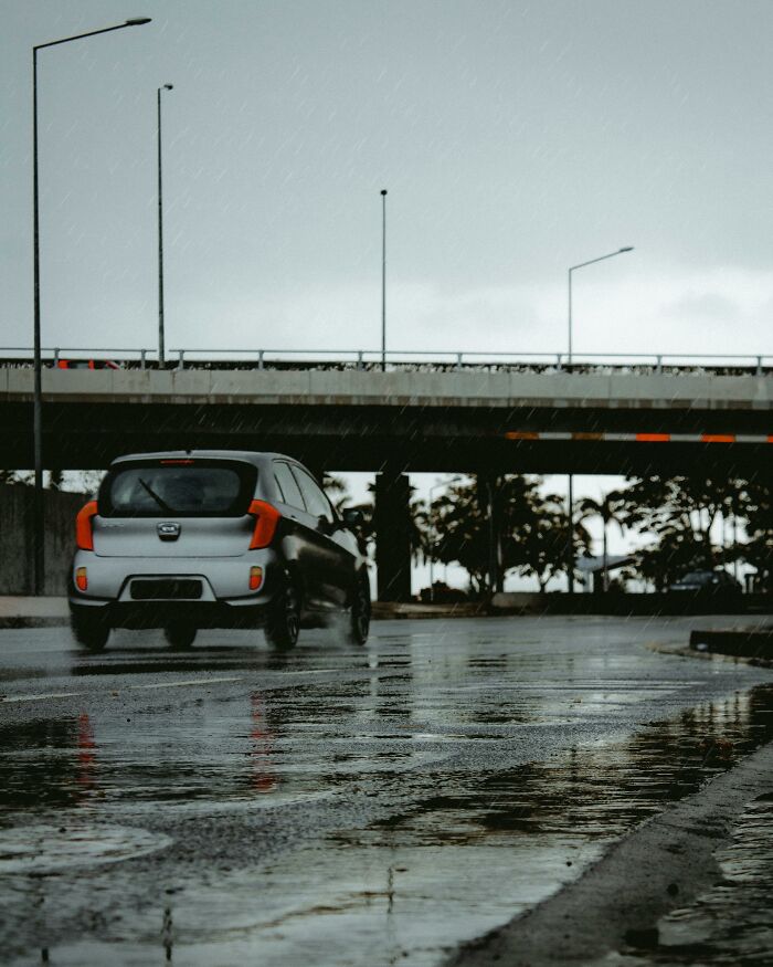 Car driving on wet street under overpass in rain