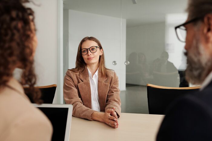 Woman in glasses at a table with two others, a scenario where social cues might be hilariously misread.