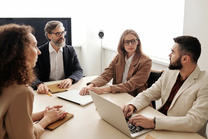 Four people in a meeting, intently listening or speaking, having hilariously misread social cues.