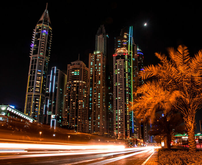 Night view of Dubai skyline with illuminated skyscrapers and palm trees, highlighting the city where the influencer was arrested.