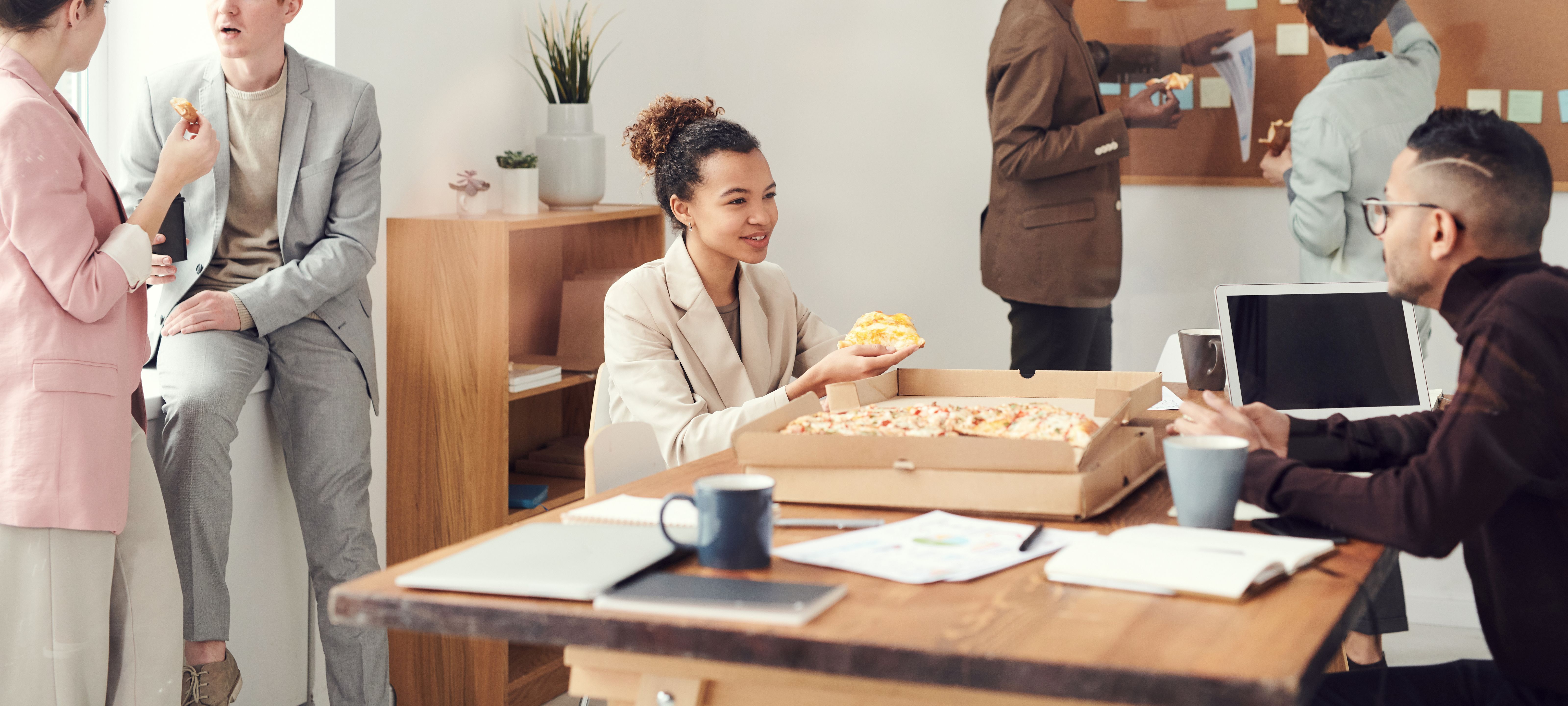 Coworkers enjoying pizza and casual conversation in an office setting, highlighting a normal work environment before an ableist Karen.