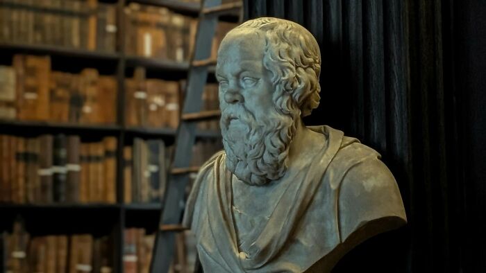 Marble bust of ancient philosopher with books in the background symbolizing great thinker concept Marble bust of ancient philosopher with books in the background symbolizing great thinker concept