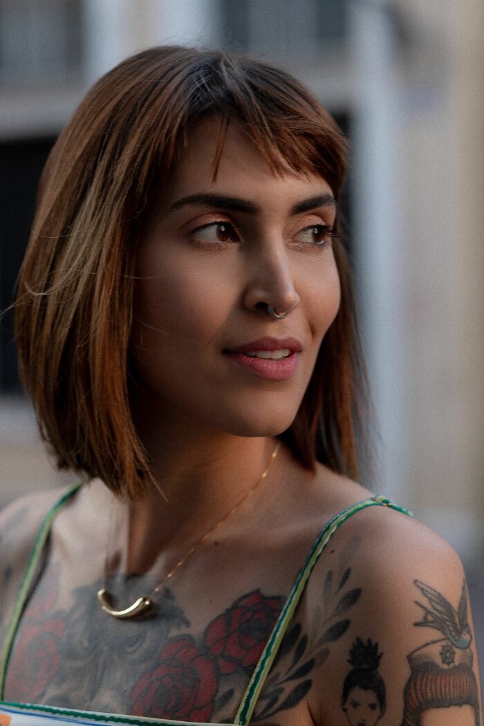 A woman with a nose ring and shoulder tattoos looks away, her style potentially being a turn off for some men.