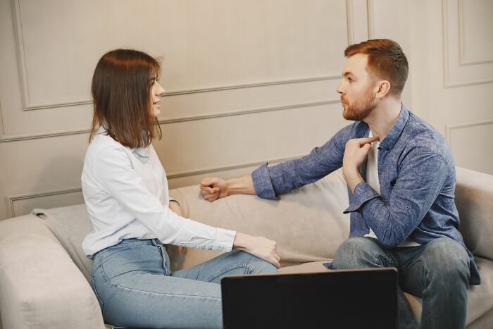 Couple in tense conversation on sofa about cheating realization