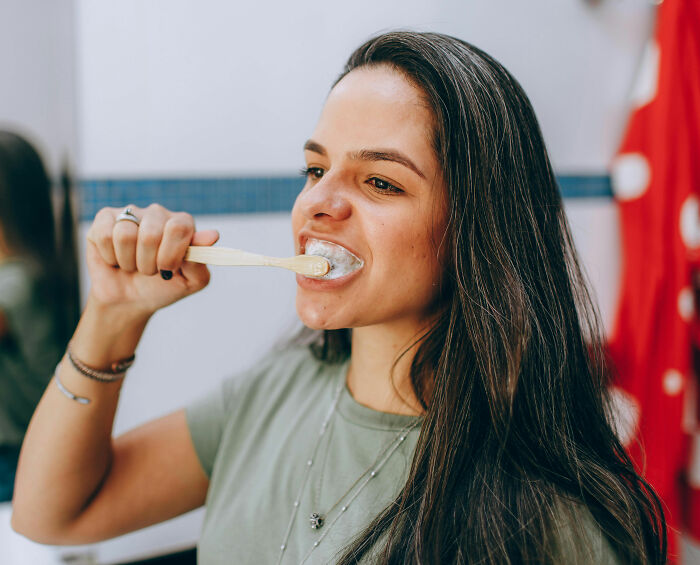 Woman brushing tongue in bathroom for better oral health