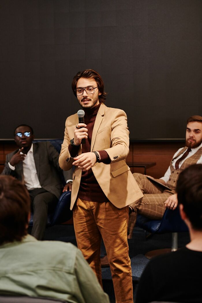A man speaking into a microphone, sharing smart hints about being a secretly very smart person.