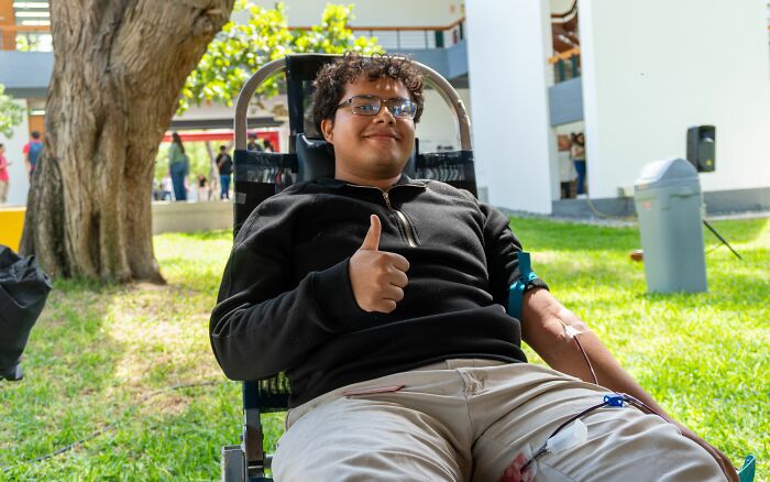 A man smiles and gives a thumbs-up while donating blood, showing how he misread social cues hilariously.