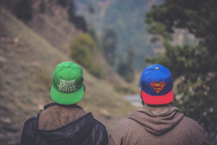Two men wearing colorful caps from behind, standing outdoors, suggesting a wild coincidence of matching hats.