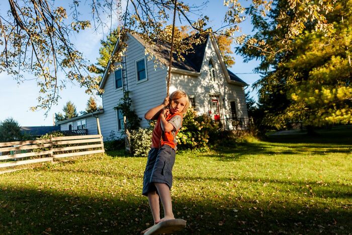 A boy on a swing in front of a house, representing an unexplained experience related to a bed compressing.