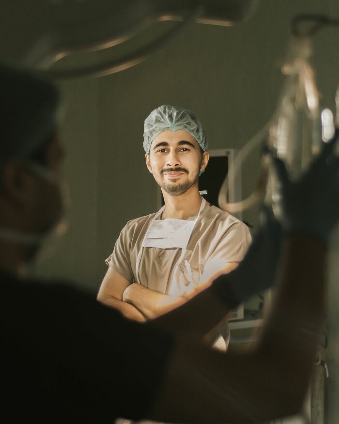 A smiling male doctor in scrubs and a hair net, a professional ready for ER visits.