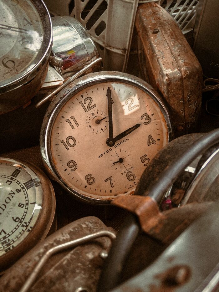 A close-up of several old, dusty clocks, representing a cool, interesting, and surprising fact about time.