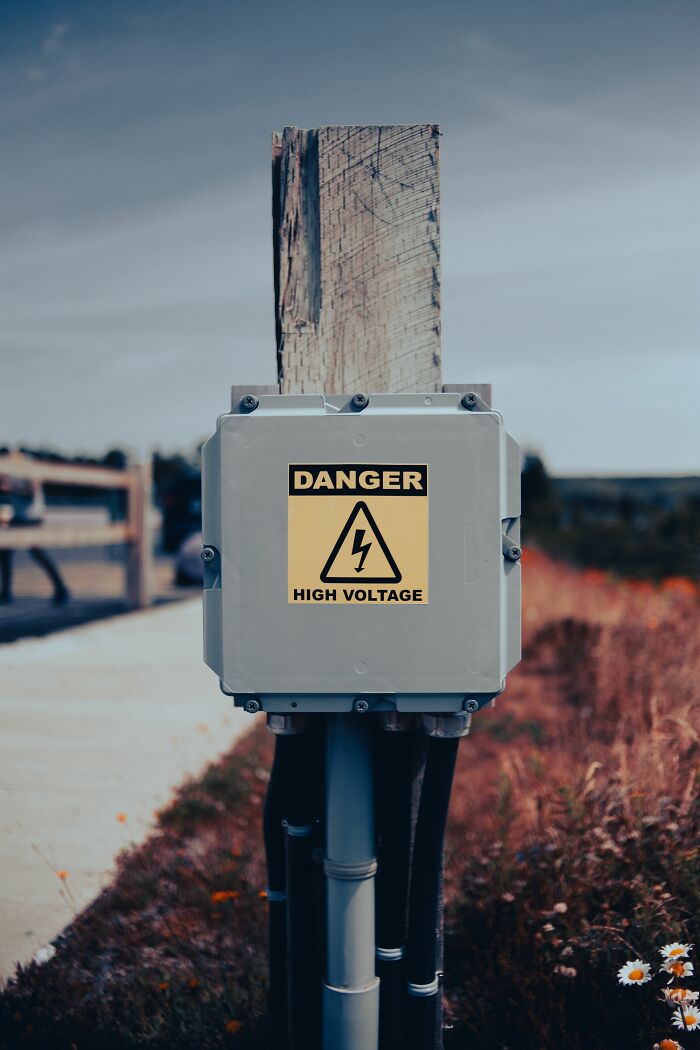 A high voltage danger sign on a wooden post, illustrating NSFW facts about human bodies and safety.