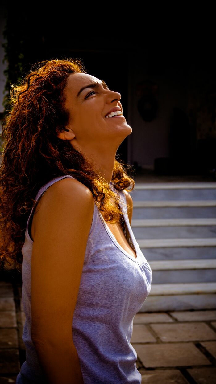 Smiling woman with curly red hair looking up, illustrating fascinating facts about human bodies.
