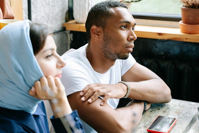 Couple sitting pensively indoors in serious conversation