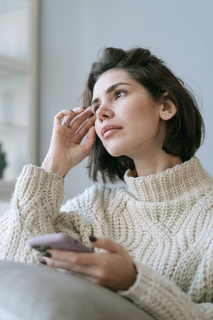 Sad woman crying while holding phone after infidelity reveal