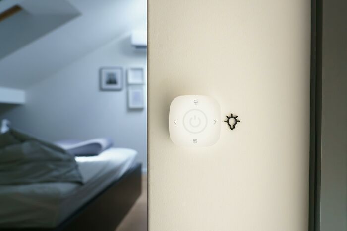 Smart light switch installed in bedroom with bed in background