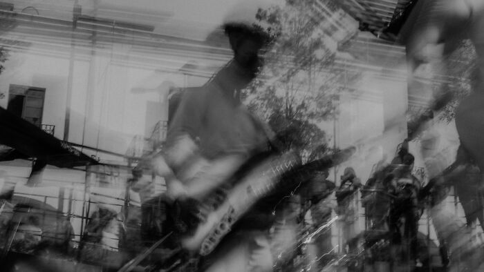 Blurry black and white image of musicians playing electric guitar and drums in a band performance Blurry black and white image of musicians playing electric guitar and drums in a band performance