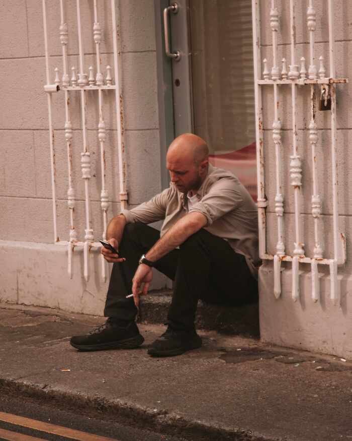 Man sitting outside smoking and looking at phone