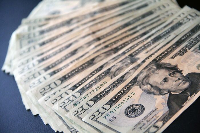 A fan of twenty dollar bills fanned out on a dark surface, symbolizing a rage mode over money.