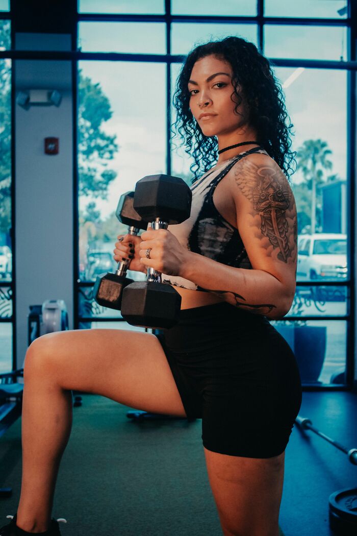 Strong woman lifting dumbbells in a gym, revealing her turn offs.