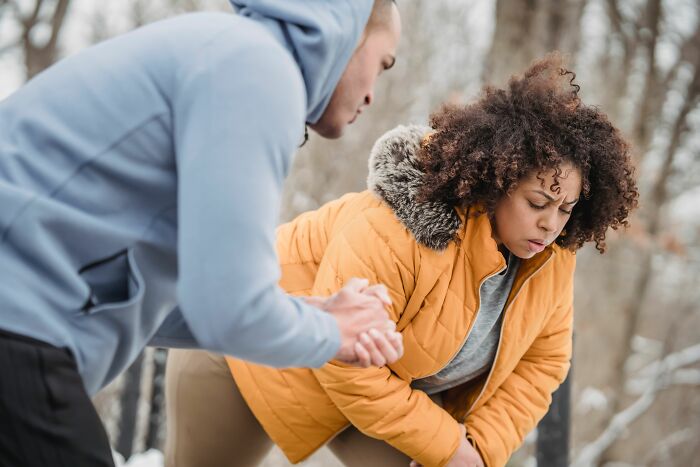A man helping a woman who appears to be in pain, illustrating human bodies in distress.