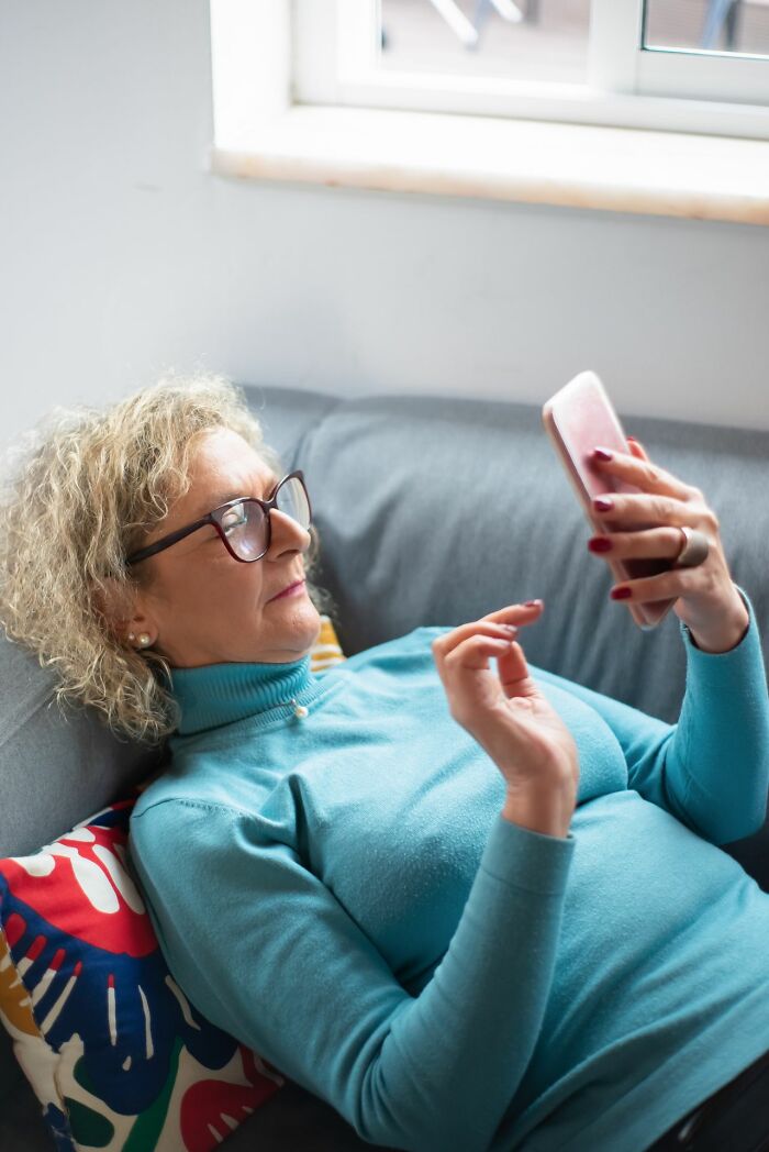 Older woman using smartphone while relaxed on couch