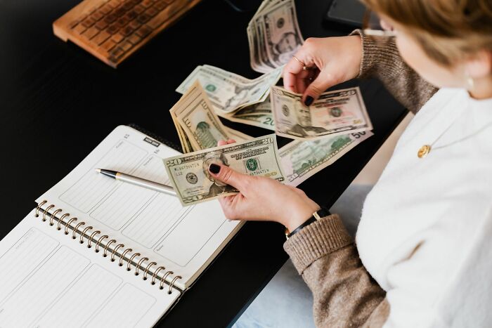 Person counting money with planner on desk representing entitled parents and money