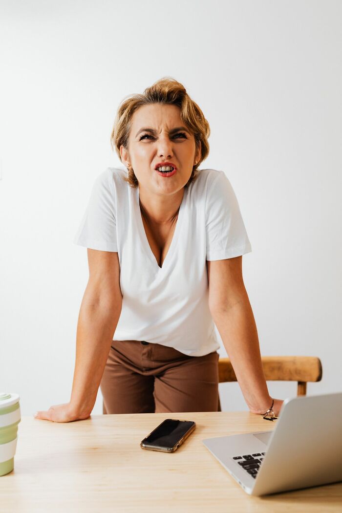 Frustrated woman leaning on table with laptop and phone