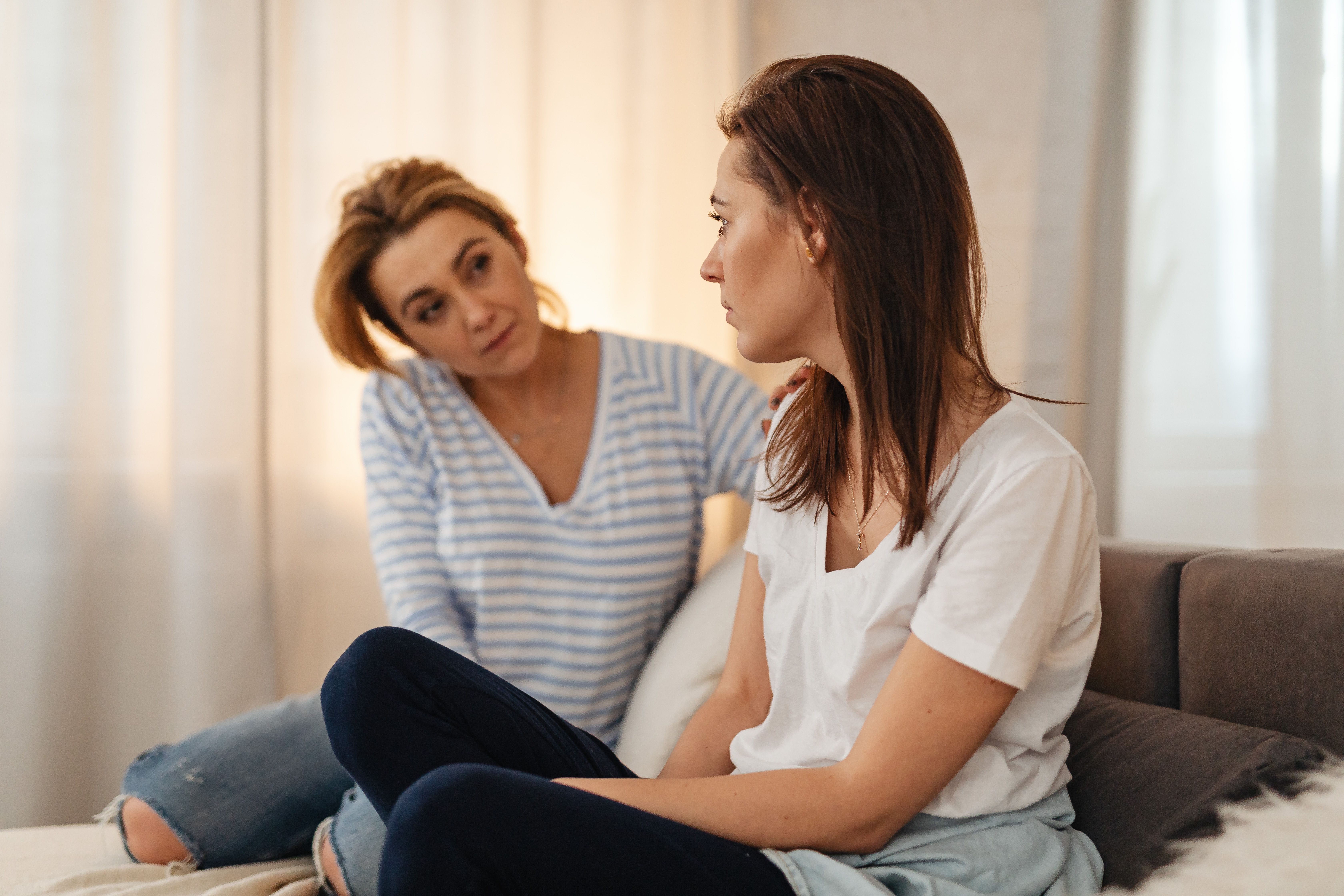 A daughter looking upset while her mom tries to console her, discussing the mom wanting a year to celebrate her birthday, delaying the wedding. A daughter looking upset while her mom tries to console her, discussing the mom wanting a year to celebrate her birthday, delaying the wedding.