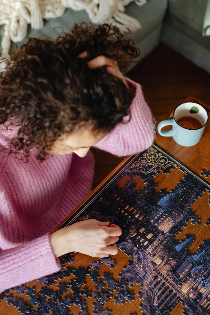 Woman puzzling over scientific jigsaw puzzle with a cup of tea nearby