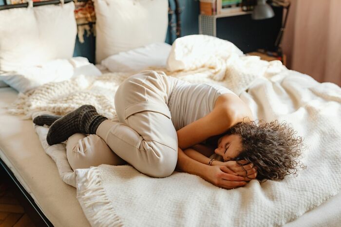 Woman curled up in bed, experiencing different types of pain.