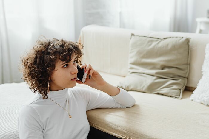 Woman on phone in living room, concerned expression