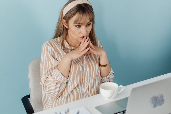 Worried woman reflecting on infidelity stories using laptop and drinking coffee